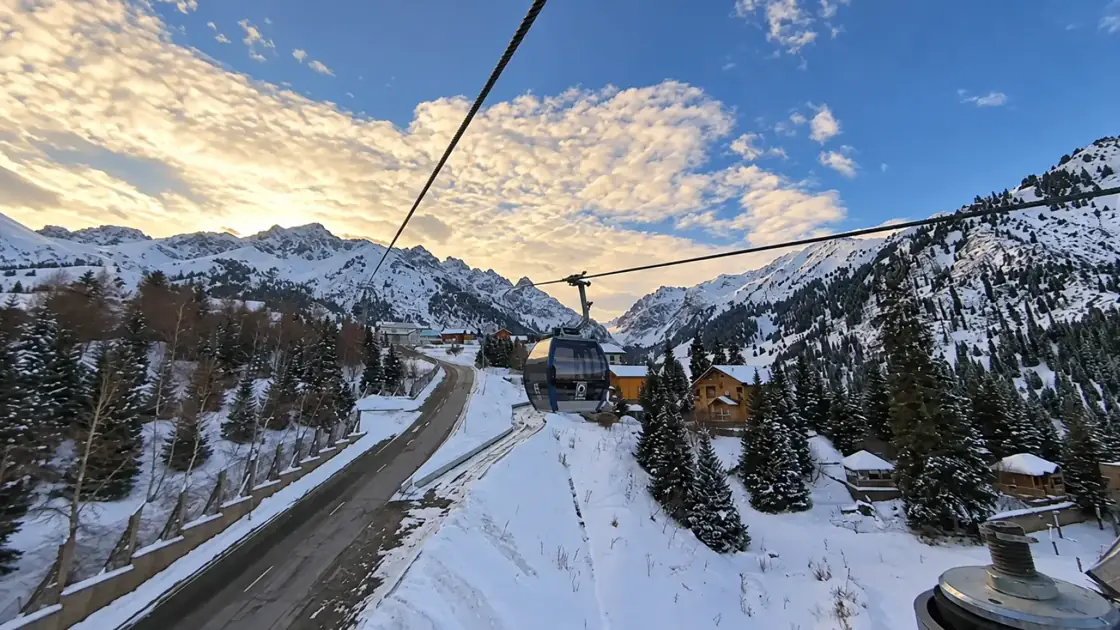 Gondola above snow-covered mountain slopes at sunset
